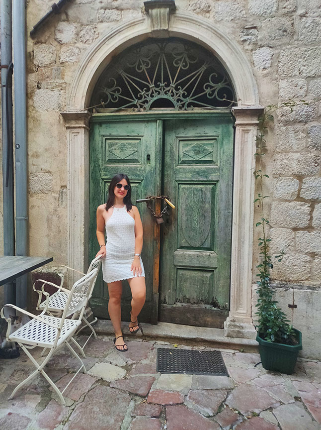 Frente a una puerta de color verde en las calles de Kotor - Que ver en Kotor