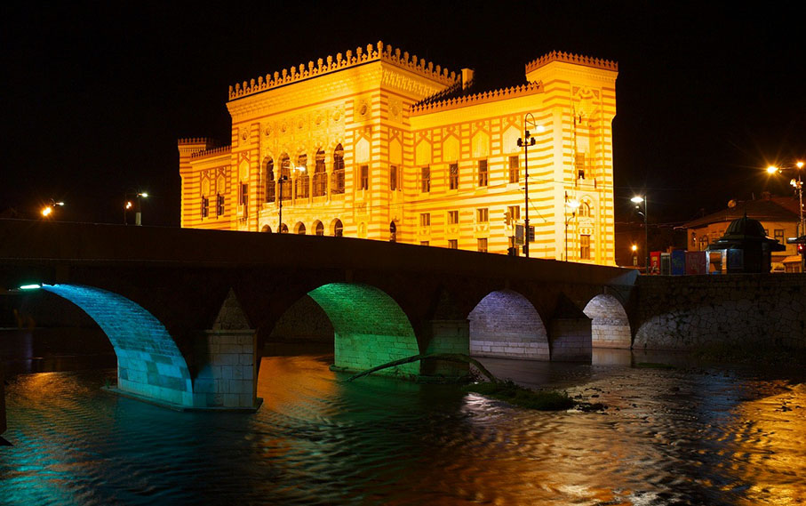 Ayuntamiento de Sarajevo iluminado con el puente - ruta por bosnia
