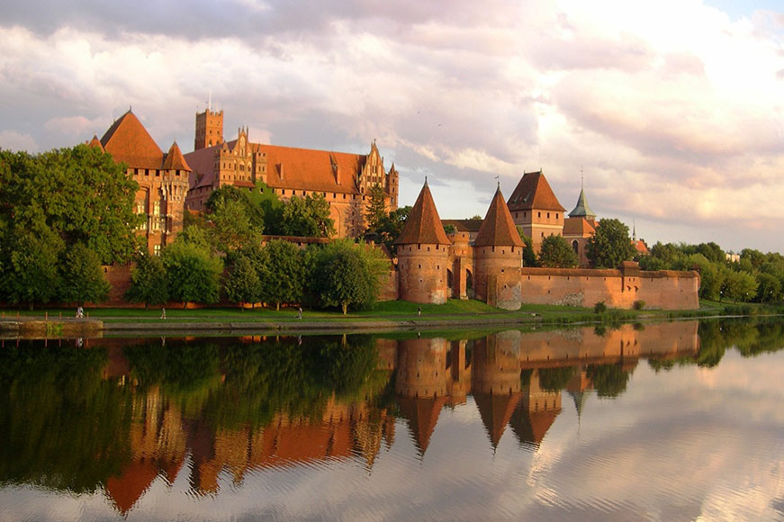 Qué ver cerca de Gdansk: el enorme Castillo de Malbork completamente de ladrillo al otro lado del río.