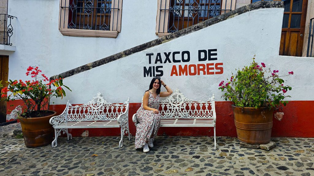 Sentada en un banco con las letras Taxco de mis amores - Viajar sola a México