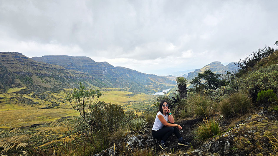Sentada en uno de los miradores del Páramo de Ocetá con un frailejón detrás y la laguna negr aal fondo - Cómo visitar la Laguna Negra