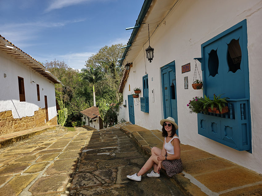 Sentada en una de las preciosas calles empedradas de Barichara con detalles en color azul. - Qué ver en Barichara, el pueblo más bonito de Colombia