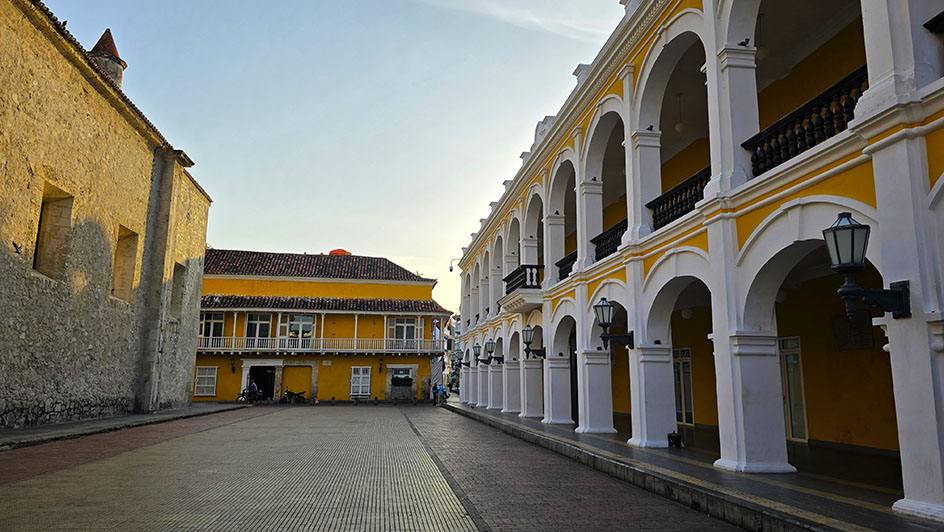 El Palacio de la Proclamación, decorado con unos portales de color amarillo preciosos a la derecha y parte de la fachada de piedra de la catedral a la izquierda en la Plaza de la Proclamación, una de las plazas más interesantes que ver en Caratgena de Indias