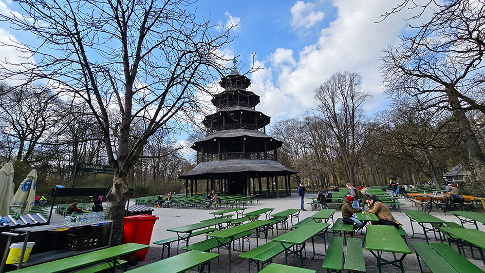 Pagoda al fondo con varias mesas de color verde del Biergarten que hay en el Jardín Inglés - Múnich en 3 o 4 días