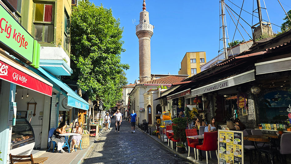 Cafeterías y restaurantes con un minarete al fondo en Vodina Caddesi, una de las mejores calles que ver en Balat