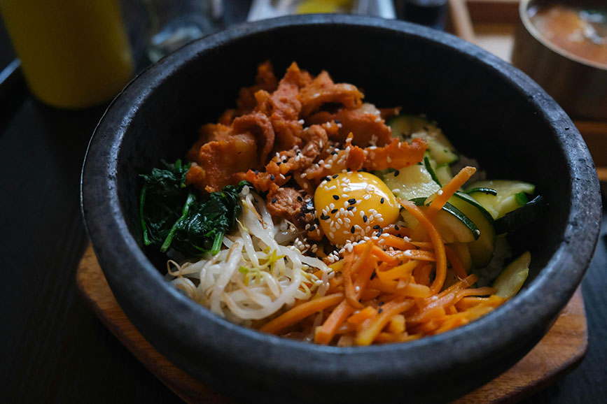 Yema de huevo crida en medio acompañada de carne cruda y verduras en un bol - Qué comer en Corea del Sur