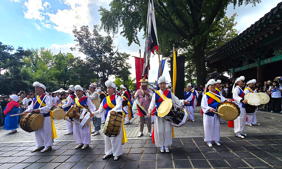 Hombes y mujeres vestidos de blanco, azul, rojo y amarillo con tambores y un escudo en el medio - Celebraciones durante el Chuseok en Corea del Sur