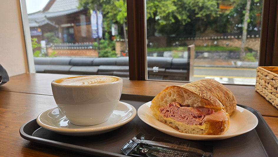 Taza de café y bocadillo de jamón york y mantequilla frente a la ventana - Dónde comer en Jeonju