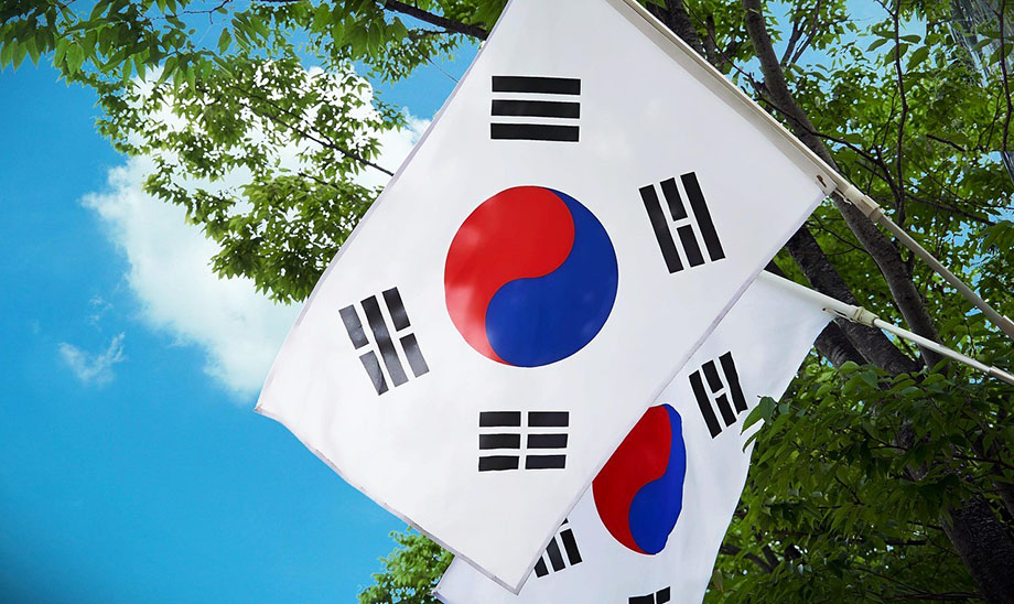 Dos banderas de Corea del Sur con los árboles y el cielo azul al fondo - Preparativos para viajar a Corea del Sur por libre