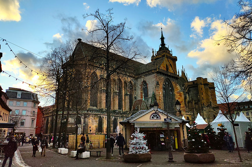 Iglesia gótica en una plaza con puestos navideños - Qué ver en Colmar