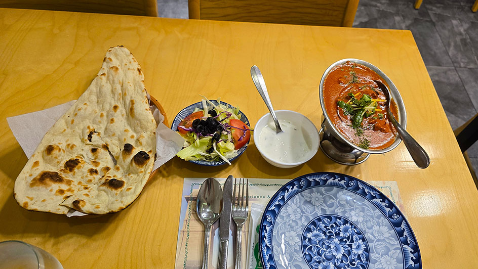 Naan a la izquierda, con un cuenco de ensalada al lado, otro de salsa blanca y el cazo de curry - Dónde comer en Seúl