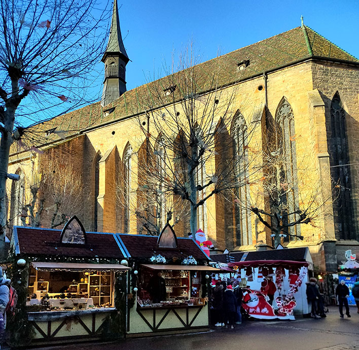 Puestos navideños y al fondo una iglesia - Qué ver en Colmar