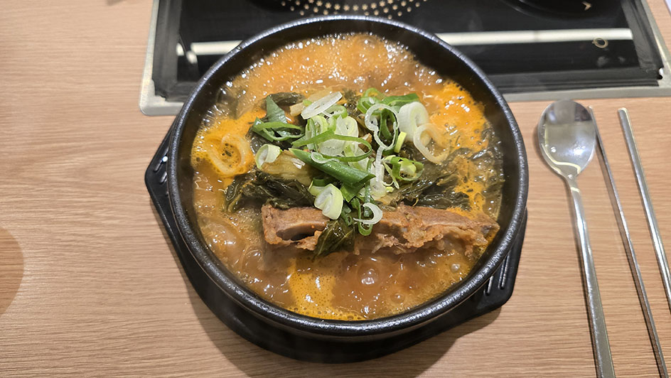 sopa coreana hirviendo con cebollino y un hueso de cerdo en lo alto - Qué comer en Corea del Sur