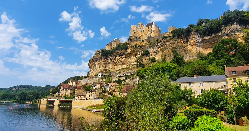 Castillo en lo alto de un acantilado con casas de piedra abajo y un río atravesando el pueblo - Los pueblos más bonitos del Périgord Negro (Périgord Noir)