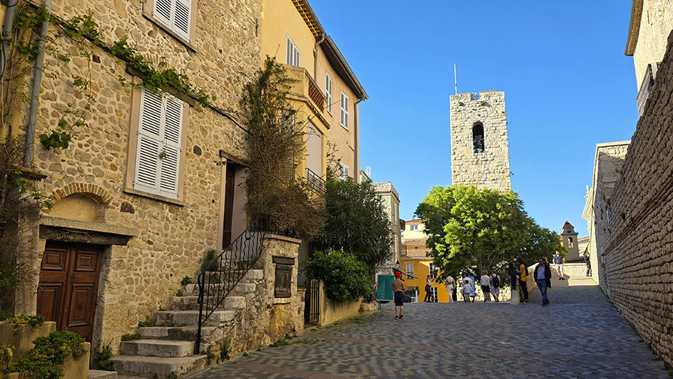 Calles empedradas con una torre y gente al fondo - Qué ver en Antibes