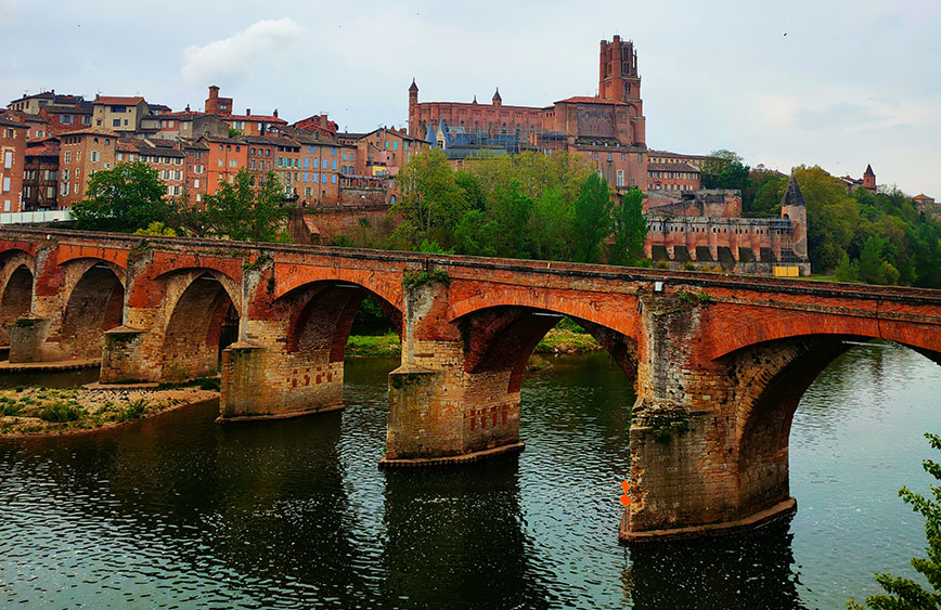 Puente Viejo sobre el río Tarn con una catedral al fondo y casas de colores rojizos al lado - Qué ver en Albi