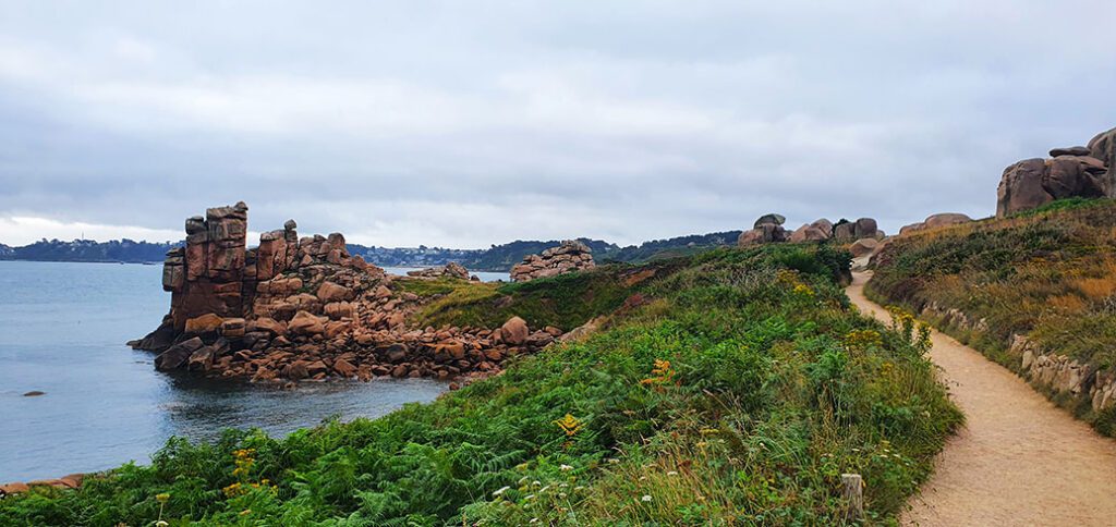 Rocas con formas curiosas en el mar con vegetacion y un camino entre medias - Cómo visitar la Costa del Granito Rosa