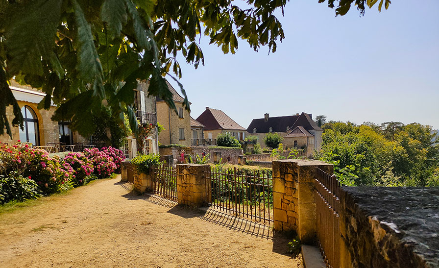 Mirador con flores rosas y casas de piedra al fondo - Los pueblos más bonitos del Périgord Negro (Périgord Noir)