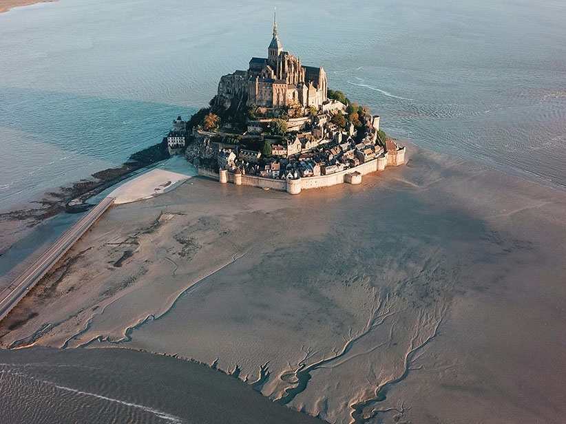 El Mont Saint Michel rodeado por una bahía con la marea baja, uno de los lugares más importantes que ver en Francia