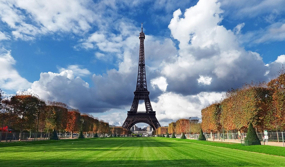 La Torre Eiffel al fondo con un campo verde y árboles a los lados - Qué ver en Francia