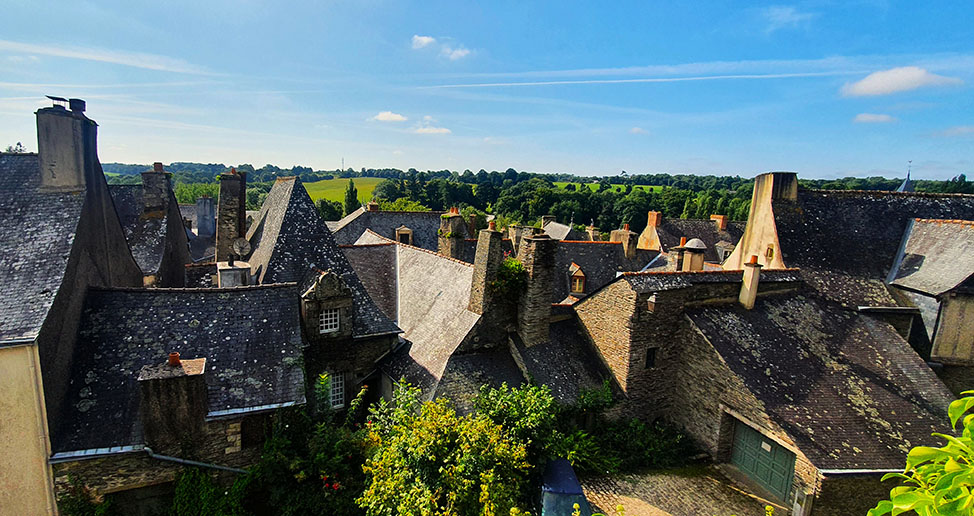 Tejados de pizarra con vegetación al fondo y el cielo azul - Los pueblos más bonitos de la Bretaña Francesa