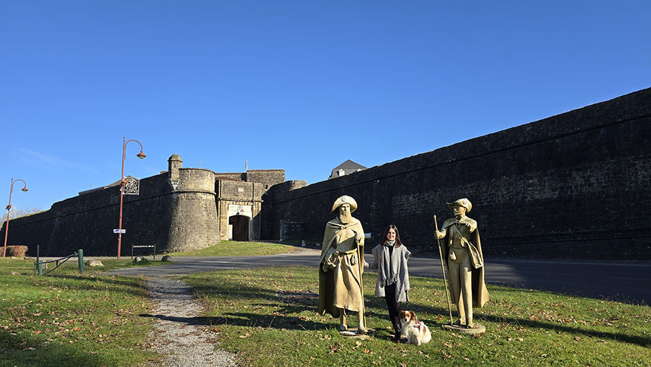 Yo junto con mi perro entre dos estatuas y con unas murallas al fondo - Qué ver en Navarrenx