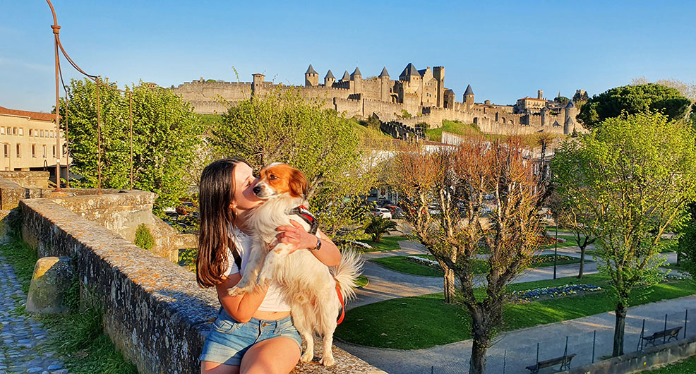 Dándole un beso a mi perro con una fortaleza y árboles al fondo - Qué ver en Carcassonne