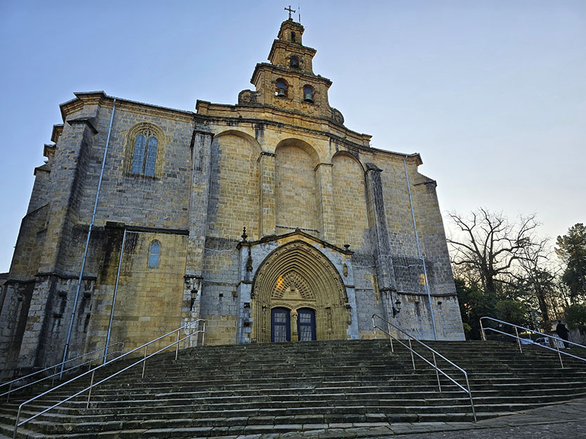 Iglesia gótica con una portada llena de relieves y dos puertas azules, con escaleras de acceso - Qué ver en Gernika