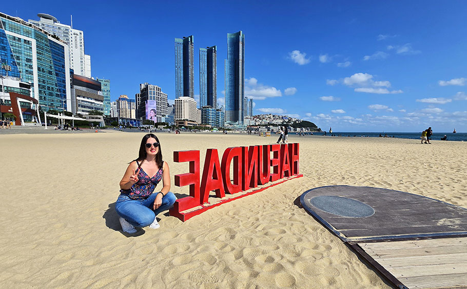 Sacándome una foto junto a las letras de Haeundae en la playa y con rascacielos en el fondo - Dónde alojarse en Busan