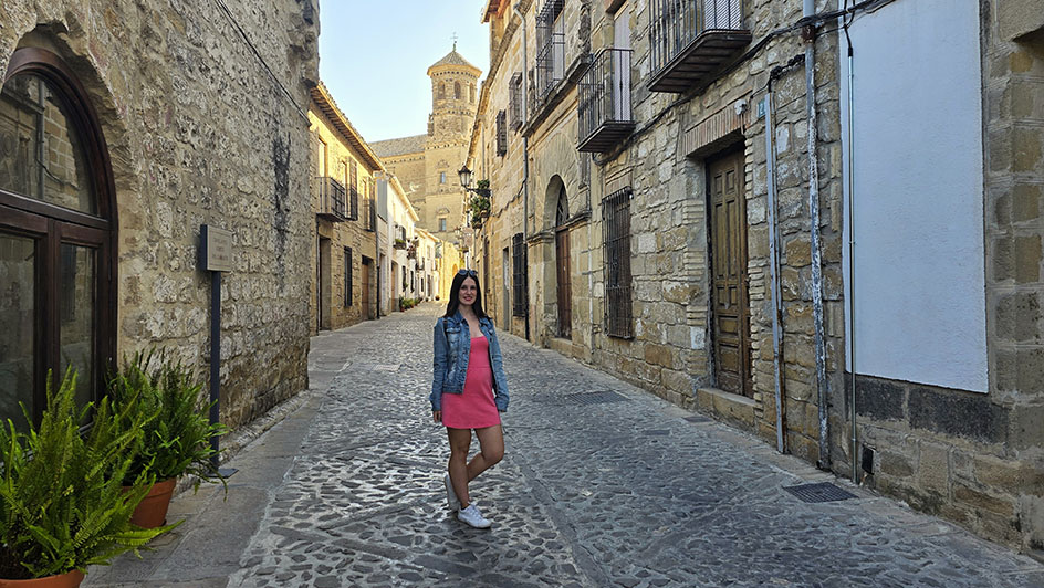 En una calle empedrada con fachadas de piedra y una torre al fondo - Qué ver en Baeza