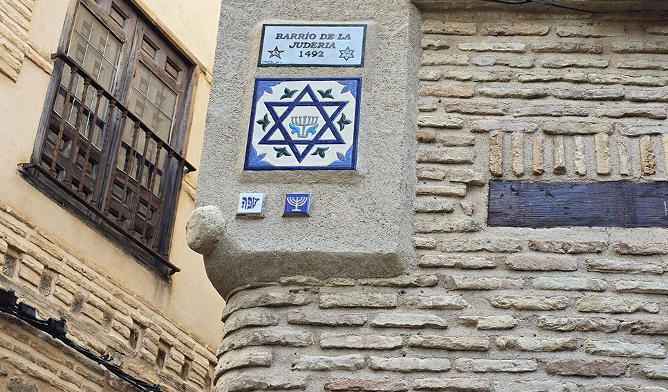 Azulejo con el símbolo judio y otro encima con paredes de ladrillo - Qué ver en Toledo