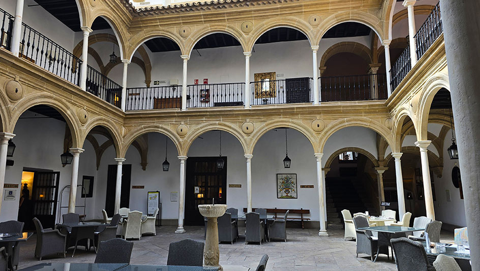 Patio arqueado de dos paltas con sillas y mesas en él - Qué ver en Úbeda