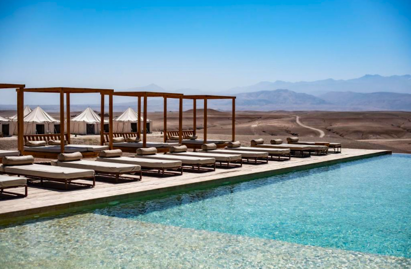 Piscina con hamacas a la izquierda y una jaimas al fondo mientras se observa el desierto - Las mejores excursiones desde Marrakech