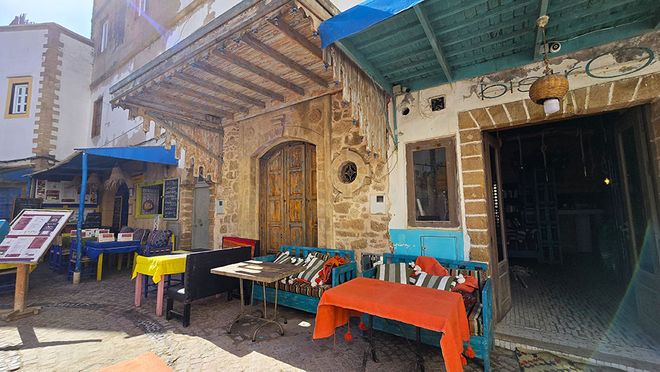 Terrazas con bancos de madera pintados y mesas coloradas, así como muchos detalles en madera de los edificios -  - Qué ver en Essaouira