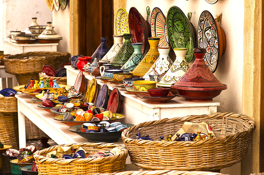 Puesto con un montón de tajines y platos de color con cestos a los lados - Qué comer en Marruecos