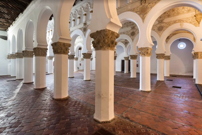 Columnas blancas con deatlles dorados y suelo rojizo - Qué ver en Toledo