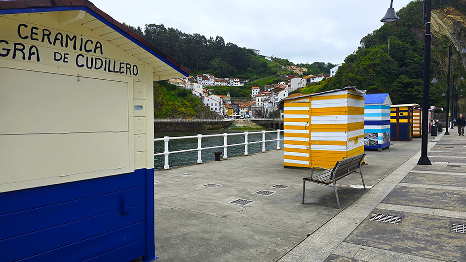Casetas de colores a rayas frente a un pueblo marinero - Qué ver en Cudillero