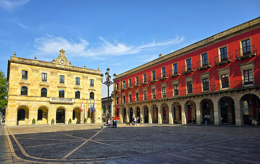 Ayuntamiento al frente y soportales de color rojizo a la derecha - Qué ver en Gijón