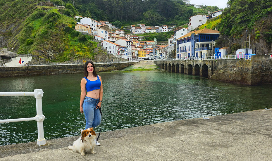 Sujetando a mi perro frente a un pueblo pesquero de casa de colores en la ladera de una montaña - Qué ver en Cudillero