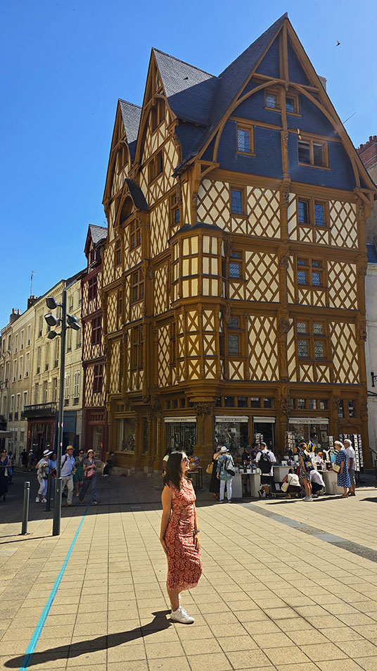 Turista frente a la casa de entramado de madera de color amarillo llamada la Maison d'Adam, la más bonita que ver en Angers