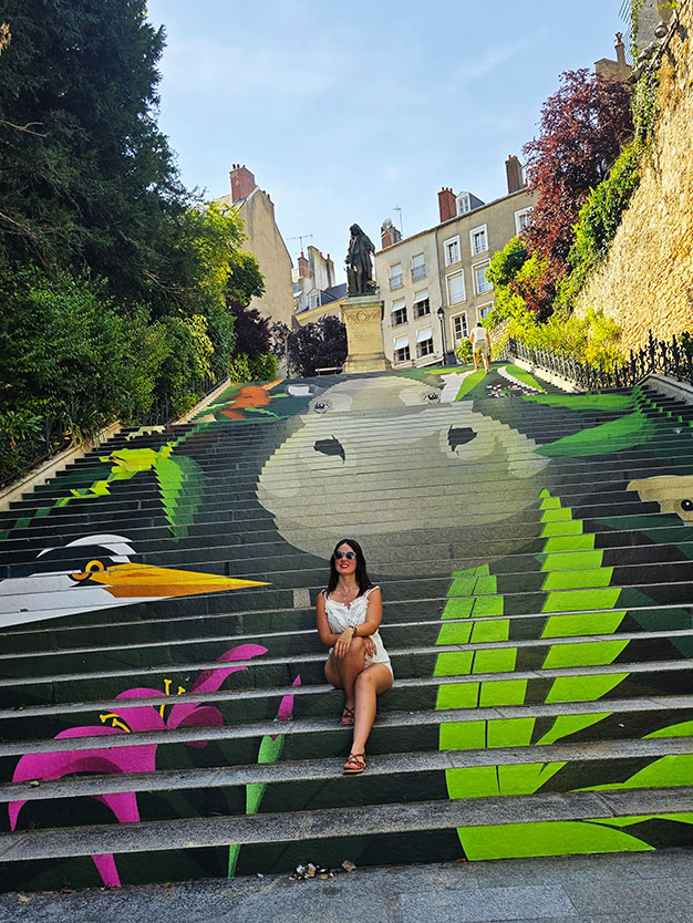 Turista sentada en las coloridas Escaleras Denis Papin en Blois, una de las mejores ciudades para visitar el Valle del Loira en transporte público